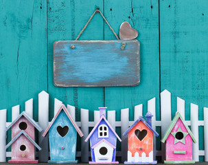 Wall Mural - Blank wood sign hanging over fence and birdhouses