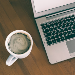 Cup of coffee and laptop on wooden table