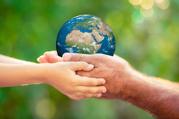 Canvas Print - Child and senior holding Earth planet in hands