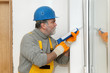 © sima - Home renovation, worker caulking with silicone door, window