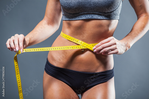 Fotografie, Obraz Woman measuring her waist with a yellow tape