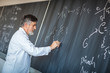 © lightpoet - Senior chemistry professor writing on the board while having a c