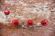 Red Sprinkler Valves Against Red Brick Background