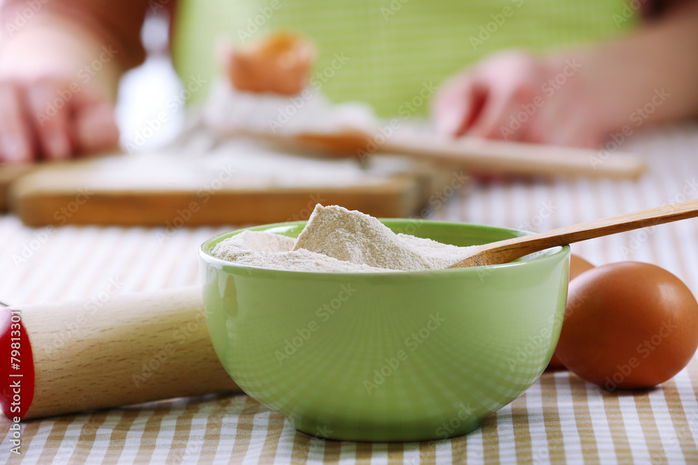 Young woman prepares dough on table close up