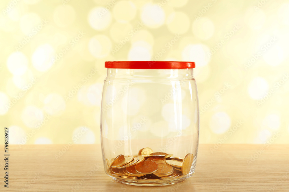 Gold coins in glass bottle on bright background