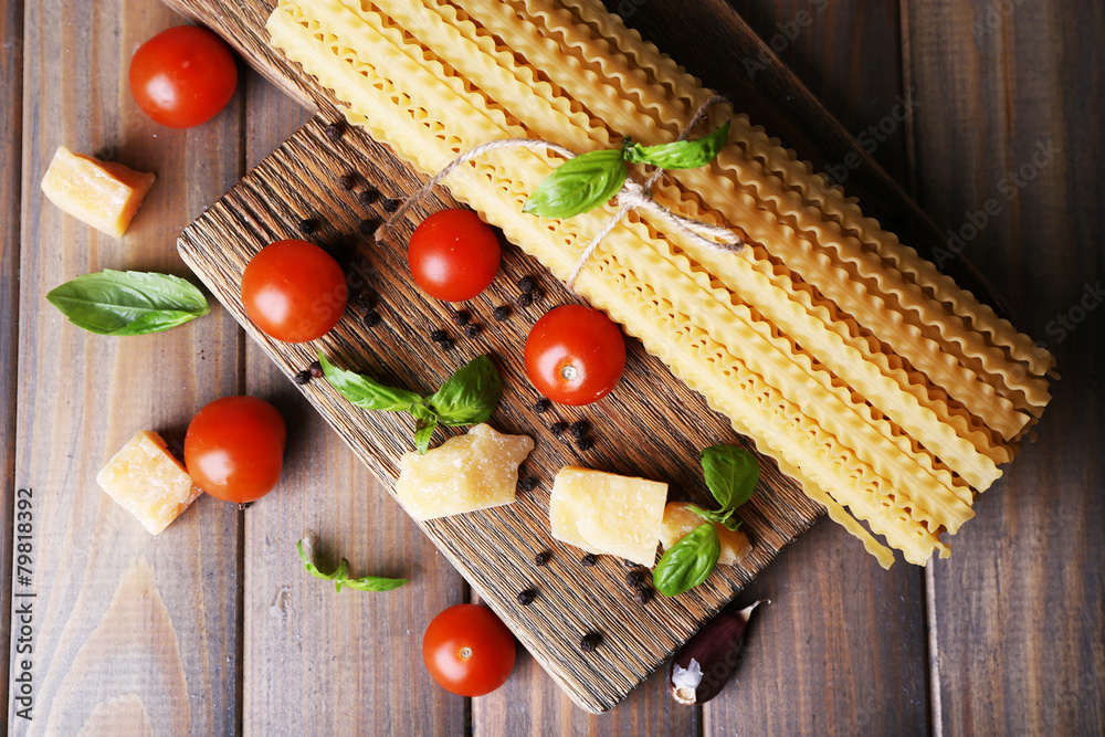 Raw pasta with cheese and vegetables on wooden background