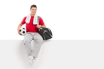 Poster - Young football player sitting on a blank billboard