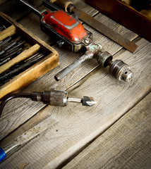 Drills in box, drill, chisel on a wooden background.