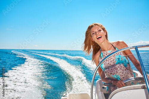 Fotografia Summer vacation - young woman driving a motor boat