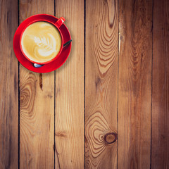 Wall Mural - red cup and latte coffee on wood table with space.