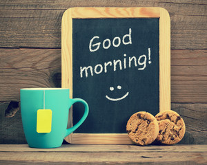 Cup of tea with cookies and blackboard with phrase Good morning!