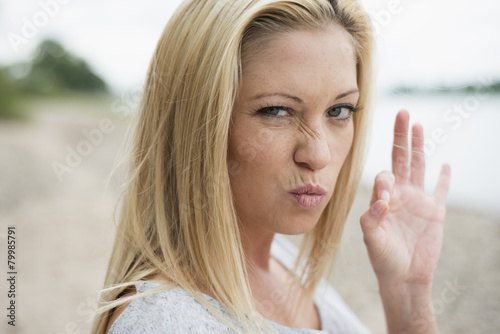 Portrait Of Young Blond Woman Pouting Mouth And Showing Ok Sign