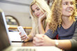 © Westend61 - Two female students with cell phone and laptop in a library