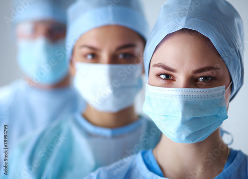 Fotografía Surgeons team, wearing protective uniforms,caps and masks