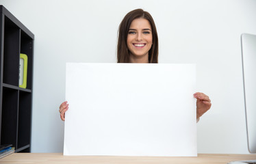 Poster - Smiling businesswoman holding blank card in office