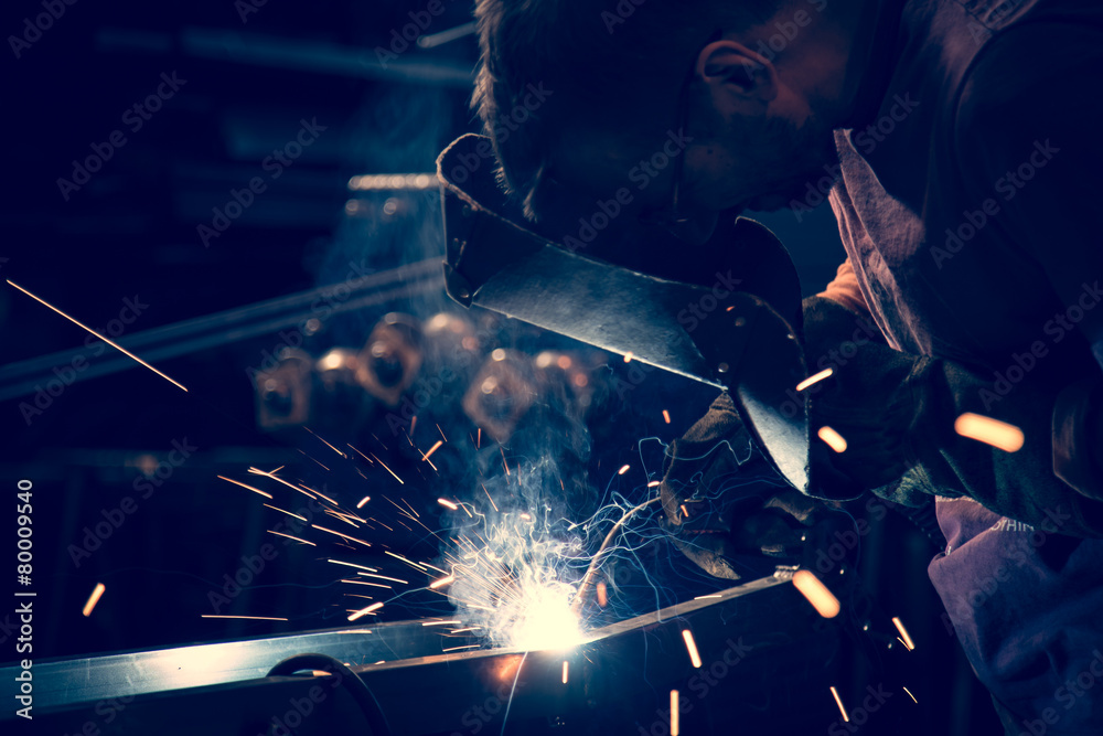 Employee at the factory welding steel using MIG MAG welder. - obrazy, fototapety, plakaty 