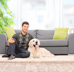 Poster - Young man sitting on the floor with his dog at home