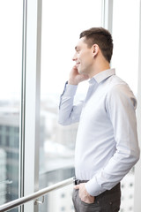 Wall Mural - smiling businessman with smartphone in office