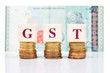 © ThamKC - GSTconcept with stack of coin and Malaysian Ringgit as backdrop