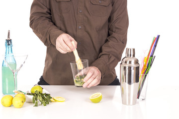 Bartender preparing mojito cocktail drink, with limes, ice and b