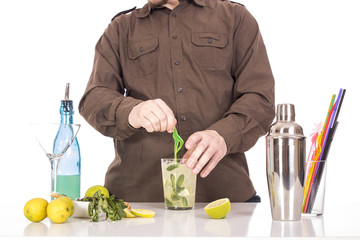 Bartender preparing mojito cocktail drink, with limes, ice and b