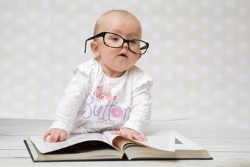 Funny baby girl reading a book