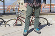 © Mr.X - Closeup of man’s legs standing inform of a vintage bicycle