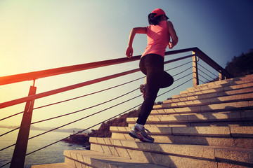 Wall Mural - young fitness woman running on seaside stone stairs