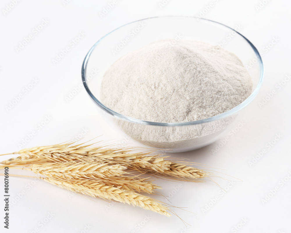 Glass bowl with flour and ears isolated on white