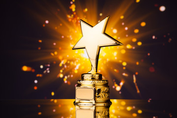 gold star trophy against shiny sparks background