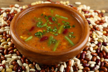 Canvas Print - Bean soup in bowl and raw beans on wooden table background