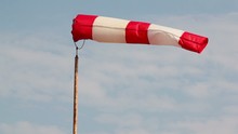 Wind Sock Flutters At Background Of Sky With Clouds