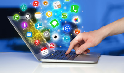 Fototapete - Hand pressing modern laptop with mobile app icons and symbols