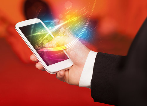 Hand holding smart phone with abstract glowing lines