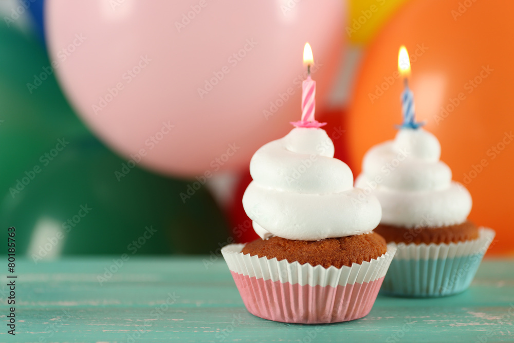 Delicious birthday cupcakes on table on bright background