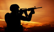 Soldier shooting with his weapon, rifle at sunset. War