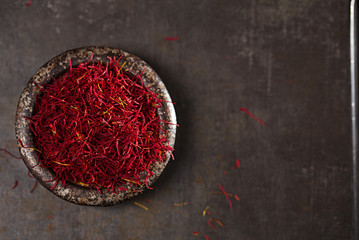 saffron spice threads and powder  in vintage iron dish