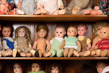 Antique Dolls Sitting In A Cabinet