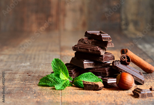 Fotografie, Obraz Stack of chocolate slices with mint leaf,hazelnut and cinnamon.