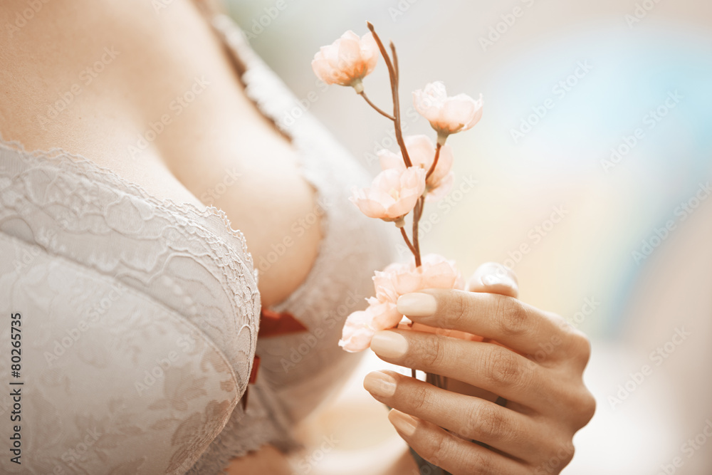 Woman in brassiere holding Sakura flower - obrazy, fototapety, plakaty 