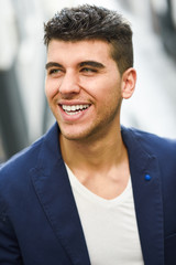 Canvas Print - Handsome young man with blue eyes posing near a wall