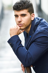 Wall Mural - Handsome young man with blue eyes posing near a wall