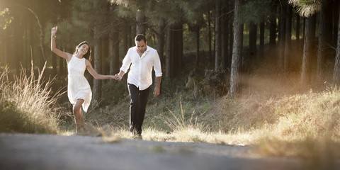 happy Indian couple walking outdoors on dirt road in field