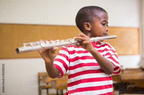 Fotomural Cute pupil playing flute in classroom