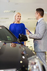 Wall Mural - happy woman with car dealer in auto show or salon