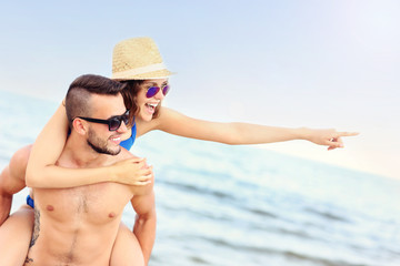 Poster - Young couple pointing at something at the beach