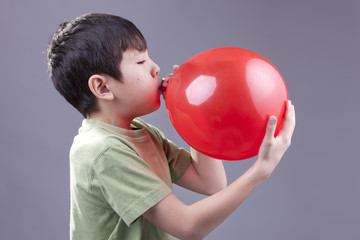 Boy blows up balloon.