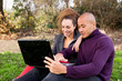 © michael spring - young couple in the park looking at laptop