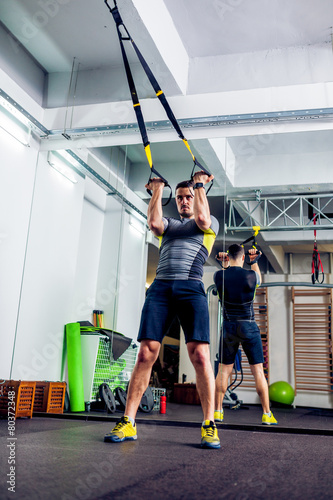 Nowoczesny obraz na płótnie Crossfit instructor at the gym doing TRX Excersise