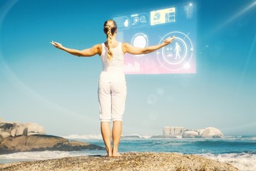 Poster - Blonde woman standing on beach on rock with arms out